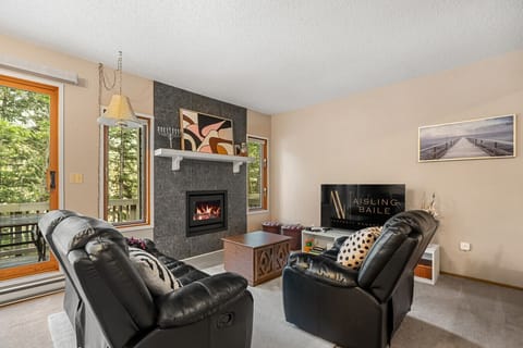 Living room with a 55` smart TV with cable, wood-burning fireplace, cozy seating options & walkout access to the balcony.