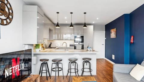 Bright, open-plan lounge and kitchen with a warm, relaxed feel. Comfortable seating, smart TV, and a kitchen island with bar stools create an easy space to unwind, cook, and socialise.