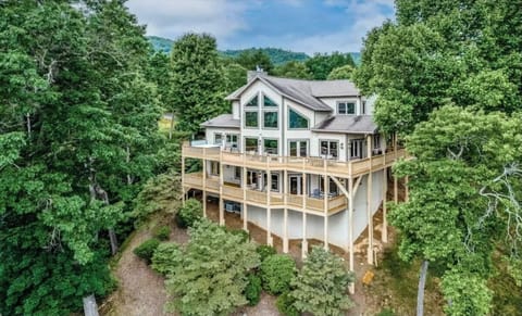 Aerial view of Summit Escape showcasing the three-story cabin surrounded by trees in Bryson City, NC. Located near the Great Smoky Mountains with multiple covered decks overlooking the landscape.