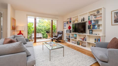 Light and bright open plan living space with smart TV and large doors onto courtyard