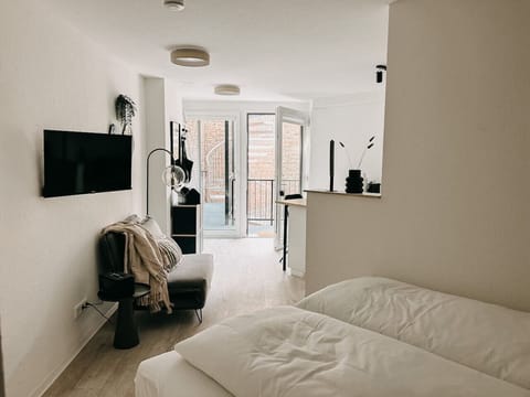 Ein Raum voller Licht und Leben – das offene Design verbindet Schlaf- und Wohnbereich harmonisch und führt direkt auf den Balkon. Perfekt für entspannte Stunden mit Blick ins Freie.