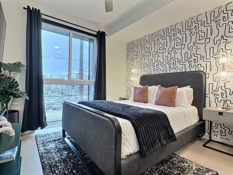 Relax in a cozy bedroom with city views inside a furnished apartment.