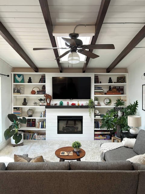 Cozy living room ready to entertain with a 55" smart TV, gas fireplace and floor to ceiling garden-view windows 