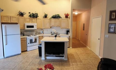 Open kitchen and living area with tile flooring, full-size appliances, breakfast bar, and easy access to the main hallway.