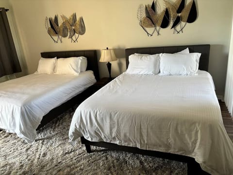 Spacious bedroom featuring two comfortable beds, dresser storage, and a bright, relaxing setup.