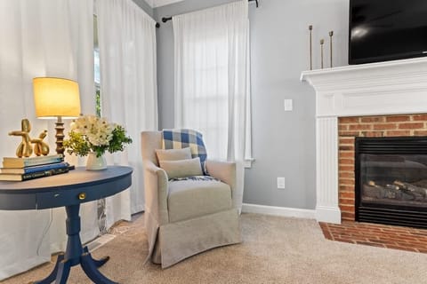 This charming corner offers a perfect spot for reading by the brick fireplace. The comfortable armchair and warm decor create a peaceful retreat within the home.
