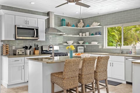 Coastal kitchen: stainless appliances, island seating & sunny style.