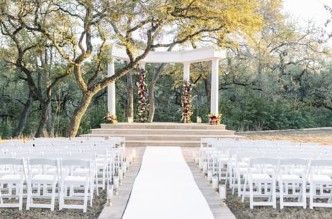 Elegant outdoor ceremony setup surrounded by nature and golden light.