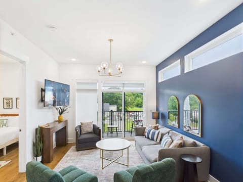 Bright open floor living space featuring a smart flat-screen TV, designer furnishings, and a private balcony entrance.