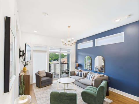 Bright open floor living space featuring a smart flat-screen TV, designer furnishings, and a private balcony entrance.