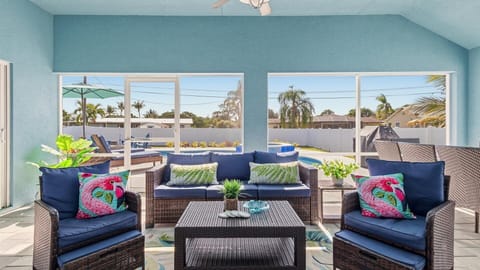 This bright, screened-in patio offers a comfortable spot to relax between the living area and the pool, featuring cozy wicker seating, vibrant décor, and a dining set perfect for enjoying meals outdoors.