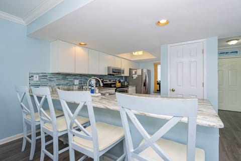 This modern kitchen features sleek stainless appliances, a stylish backsplash, and a breakfast bar perfect for casual dining
