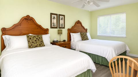 Spacious bedroom featuring two beds, ceiling fan, sitting area, and a clean, relaxing layout.