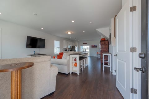 Bright open layout with comfy seating, large smart TV, and fully equipped kitchen.
