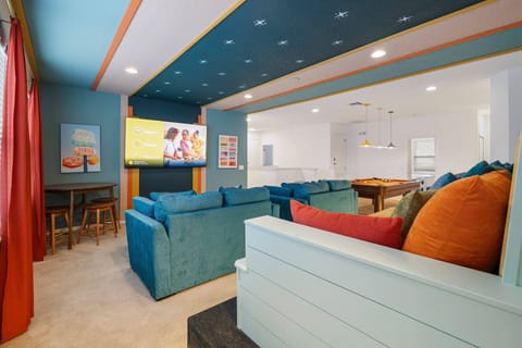 - Cozy movie lounge with plush couches and big screen TV setup  
- Retro ceiling design and playful décor create fun family vibes  
- Entertainment space perfect for group nights and game fun