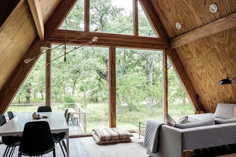 Soak in serene, hill country views through the floor-to-ceiling windows in the living room - complete with a soft, sectional sofa.