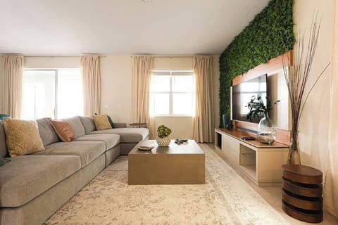 In this luminous and contemporary living space, expansive windows frame, has a view of the pool area, infusing the room with natural light and a sense of openness, creating an inviting ambiance for relaxation and entertainment.