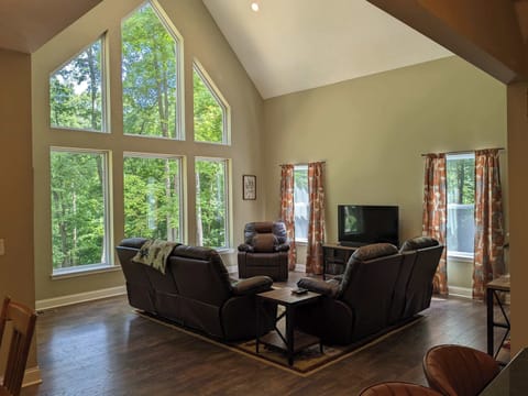 Living Room: Sunlit sanctuary with towering windows, plush seating, and nature views galore!