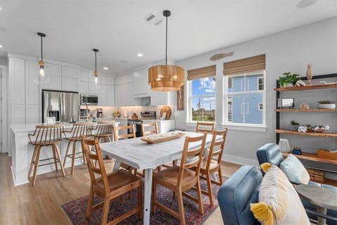 Bright dining room with seating for multiple guests and open access to kitchen and living areas.
