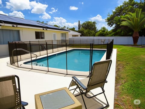 Pool with safety fence and loungers in backyard