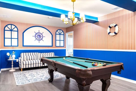 Nautical-themed game room with pool table, bold colors, and cozy seating
