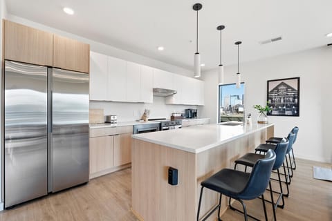 Modern white cabinetry, stainless steel appliances, kitchen island, and a view of the city skyline