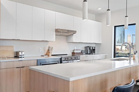 Modern white cabinetry, stainless steel appliances, and a view of the city skyline. This kitchen has it all.
