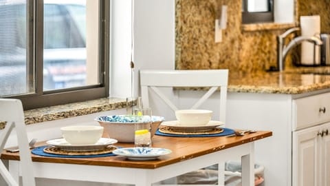 Cozy meals made easy. This well-equipped kitchen opens to a charming dining nook set for four—perfect for breakfast before the beach or a laid-back dinner at home.