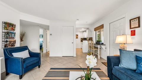 Bright and breezy coastal living room featuring a bold navy sofa, streaming TV, a collection of books, and a charming breakfast nook—perfect for relaxed mornings and cozy evenings.