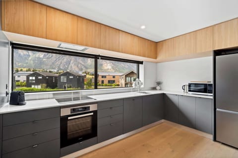 A sleek, contemporary kitchen with matte charcoal cabinetry, warm wood accents, and minimalist design accenting the Remarkables