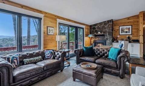 Settle into leather Chesterfield sofas beside the stone fireplace with panoramic Green Mountain views