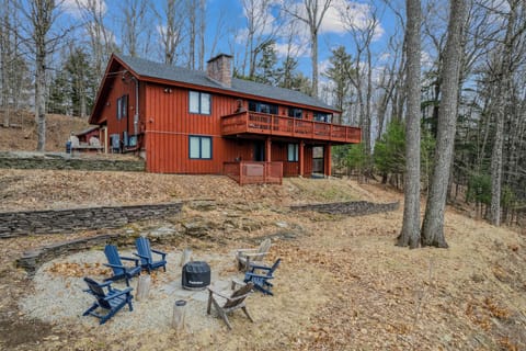 Blue Adirondack chairs around the Solo Stove fire pit with the cabin and upper deck above