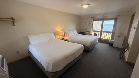 Spacious waterfront bedroom with two queen beds, a private balcony, and beautiful lake views for a relaxing stay.