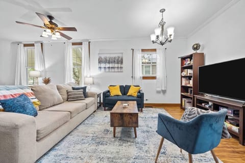 Stylish living room w/ cozy seating, TV & natural light pouring through large windows