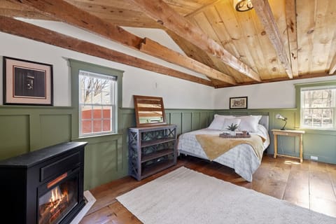 Unwind in a cozy bedroom that blends original farmhouse beams with soft, natural light