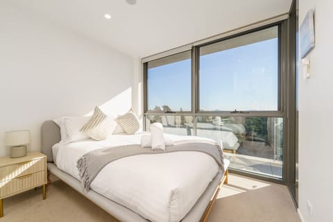 Scandinavian-style bedroom with a queen bed and scenic views of Canberra.