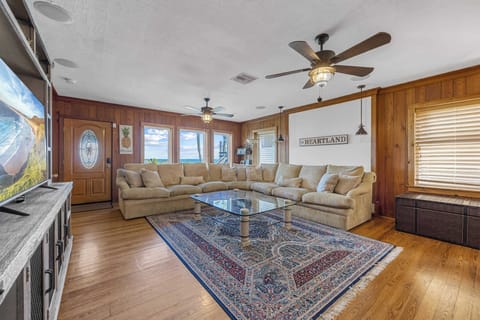 Spacious living room with ocean views and rustic wood paneling for a cozy atmosphere.