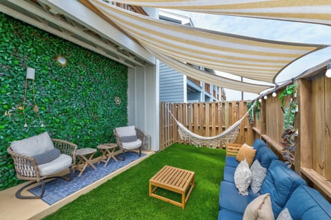 Your private backyard oasis awaits with a cozy hammock, comfy seating, and lush green walls for ultimate relaxation.