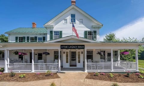 Front view of the legacy inn with a spacious porch and rocking chairs under a clear blue sky