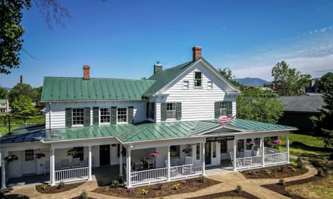 Historic inn with a green metal roof and a spacious front porch with rocking chairs