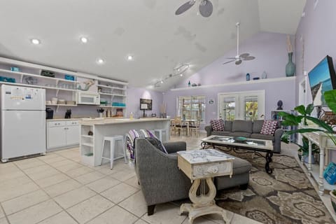 The view of the living, dining, and kitchen areas reveals an open-concept space where comfort and style seamlessly blend. The living room, with its cozy couches and high ceilings, flows effortlessly into the dining area, perfect for family meals or entert