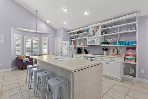 The view of the kitchen is bright and open, with modern appliances and plenty of counter space for cooking and entertaining. The sleek island with high chairs invites casual dining or conversation while meals are being prepared. Cabinets and shelves are n