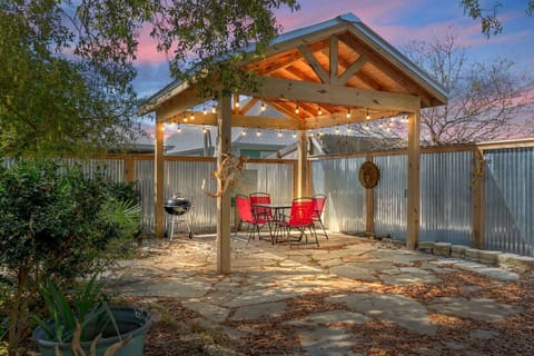 A charming wooden gazebo sits gracefully in the backyard, surrounded by blooming flowers and dappled sunlight—a perfect little retreat for relaxing, reading, or sharing quiet moments with friends.  Would you like it to sound more romantic, rustic, or mode