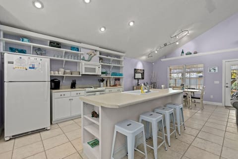 The view of the kitchen is bright and open, with modern appliances and plenty of counter space for cooking and entertaining. The sleek island with high chairs invites casual dining or conversation while meals are being prepared. Cabinets and shelves are n