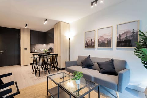 Experience modern comfort in this stylish living area, featuring a cozy sofa, sleek kitchenette, and beautiful artwork for a relaxing getaway.