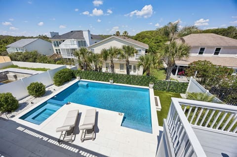 Spacious residential property with a large swimming pool, surrounded by palm trees and neighboring homes in a sunny coastal neighborhood.