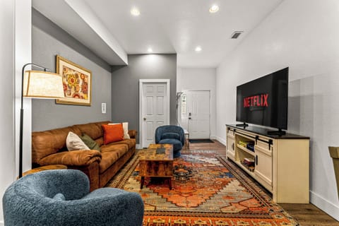 - Cozy living space with vibrant rug, plush leather sofa, and stylish blue armchairs
- Watch your favorite shows on the large smart TV with Netflix access
- Thoughtful decor and warm lighting create a relaxing ambiance