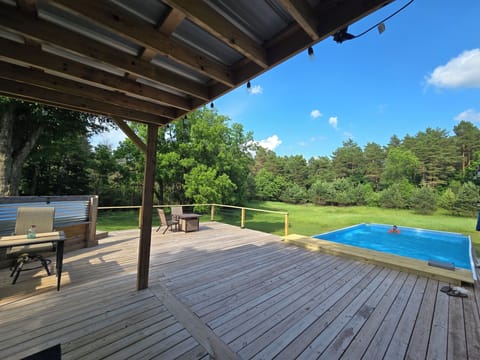 Large deck with propane fireplace, covered hot tub and large above ground pool