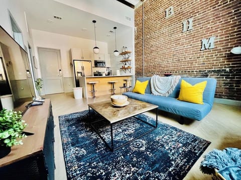 Experience comfort & style in this cozy living room inside the historic Mercantile building on Morris Ave. Fully equipped kitchen, modern decor, and access to amenities.   *please note that we have a new sofa, it is no longer a sleeper sofa*