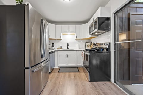 The cozy living room, filled with plush seating and vibrant artwork, seamlessly transitions into a modern kitchen featuring sleek countertops and stainless steel appliances. From there, step onto the inviting patio, perfect for relaxing or dining al fresco